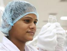 Eine Mitarbeiterin kontrolliert zwei Glasfläschchen in der Schott Kaisha Produktion im indischen Jambusar